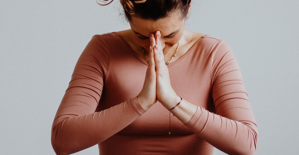 Kobieta z dłońmi złożonymi do modlitwy